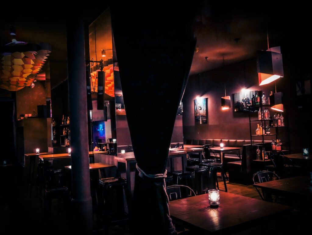 A refreshing cocktail served on a bar coaster at Sharlie Cheen Bar in Berlin Mitte, illuminated by ambient lighting with shadow patterns.